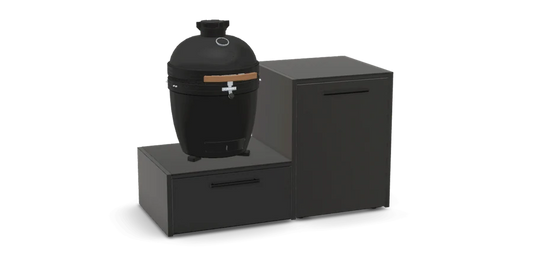 A black kamado-style grill with a small wooden handle detail, displayed on a modern black modular storage unit consisting of a drawer and a cabinet, set against a plain white background.
