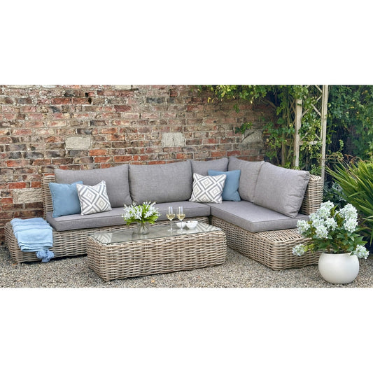 Amalfi woven outdoor corner sofa with grey seat and back cushions and matching coffee table beside a brick garden wall